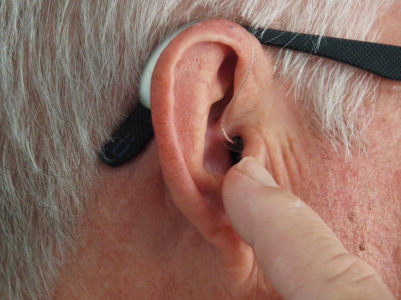 Man points at his hearing aid