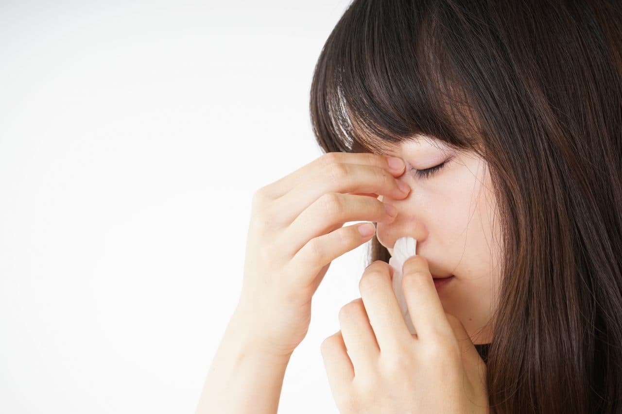 Woman treats nosebleed with tissue.