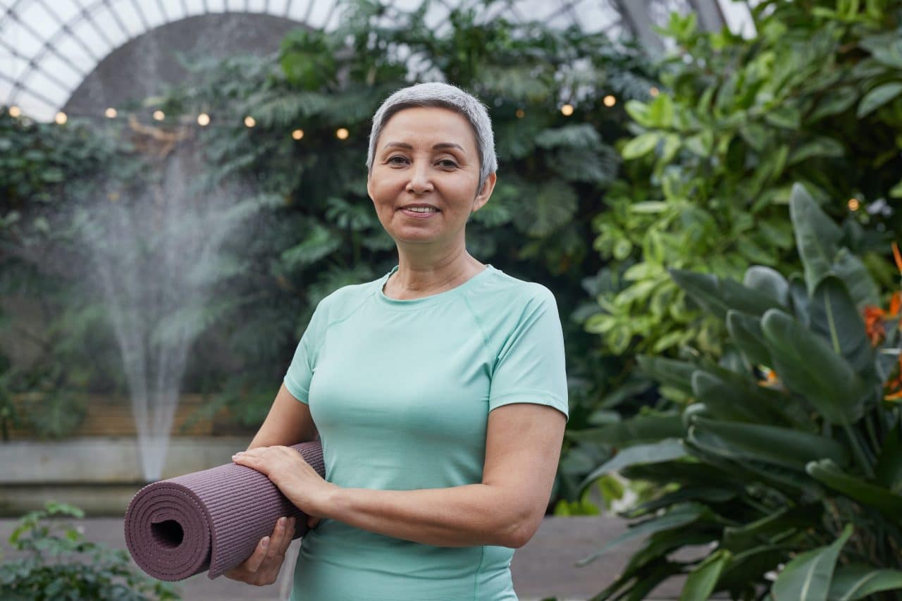 Older woman finishing yoga outside.