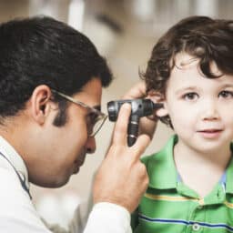 Doctor giving a toddler-aged boy an ear exam.