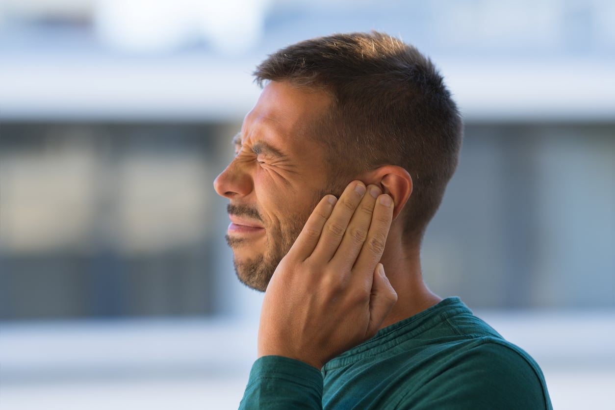 Man with tinnitus holds ear