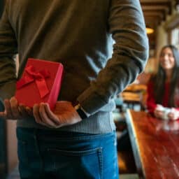 Man surprising woman with a gift while celebrating Valentines at a restaurant