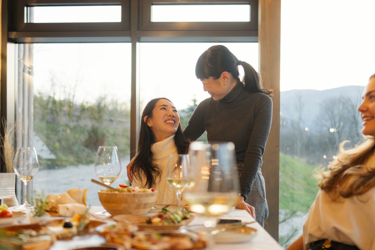 Two woman talking at the Thanksgiving dinner table.