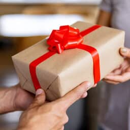 Close-up on a person giving an anniversary gift to another one - relationship concepts